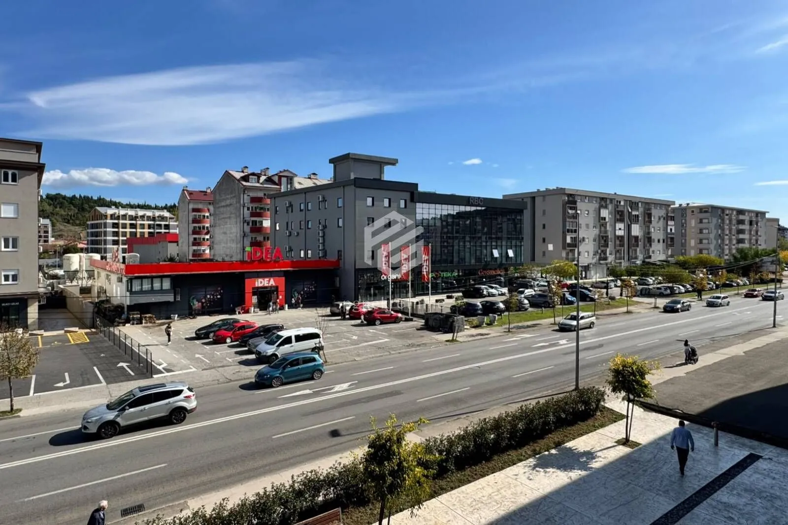 View from the terrace overlooking the city street and surrounding buildings with a parking lot.