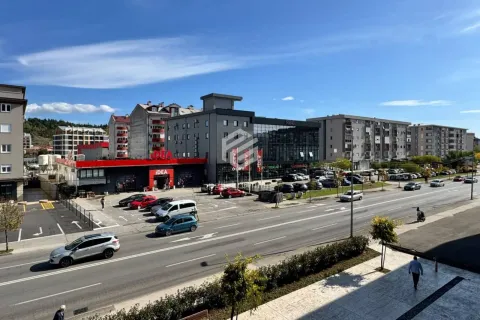View from the terrace overlooking the city street and surrounding buildings with a parking lot. - image 17