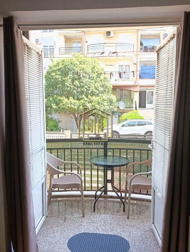 Namješten balkon sa stolom i stolicama i pogledom na okolne zgrade.