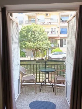 Namješten balkon sa stolom i stolicama i pogledom na okolne zgrade. - image 3