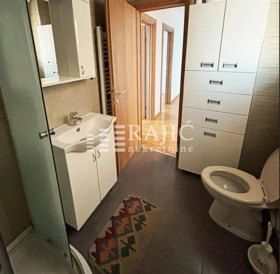 Small bathroom with a sink, toilet, and white cabinet.