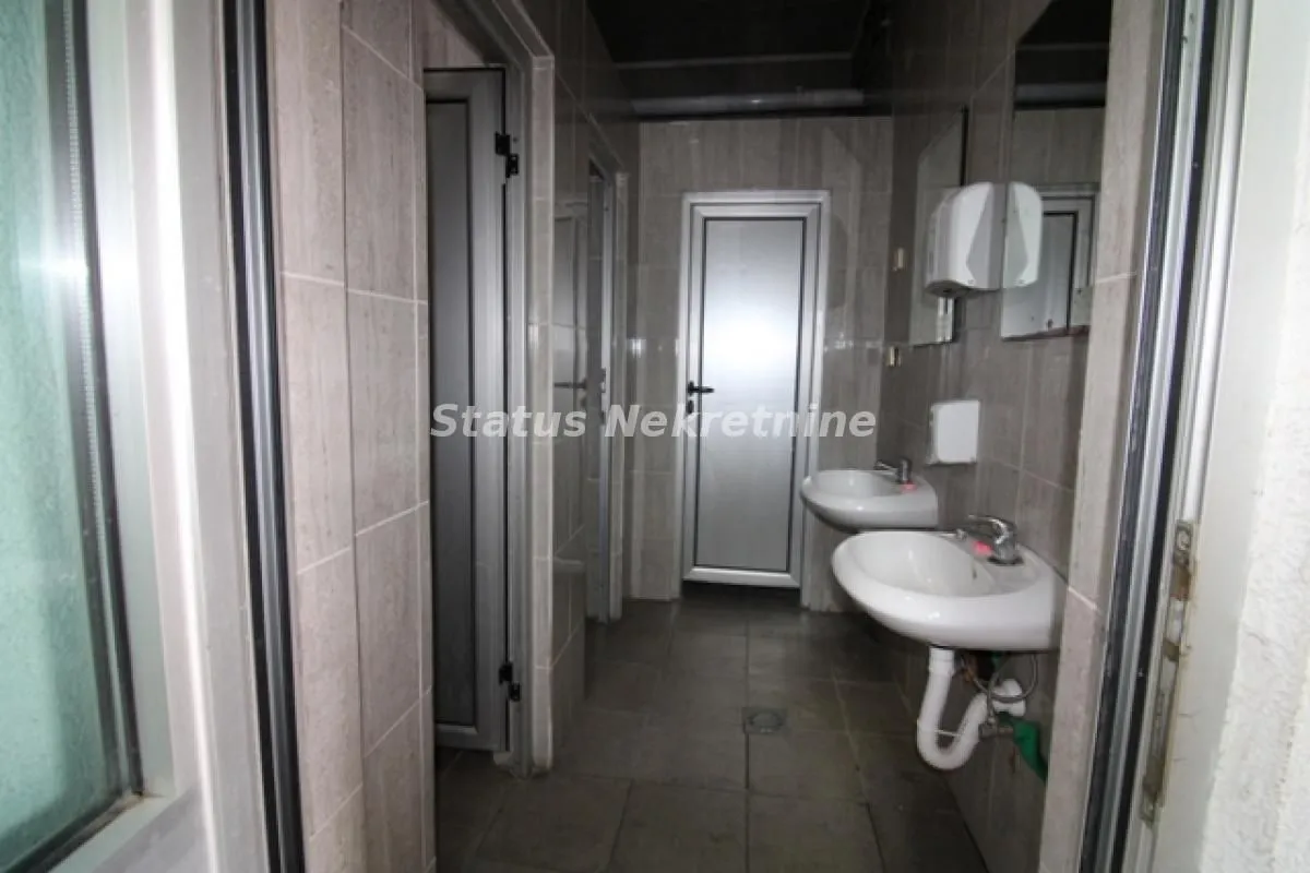 Tiled bathroom with washbasins and a door in the background.