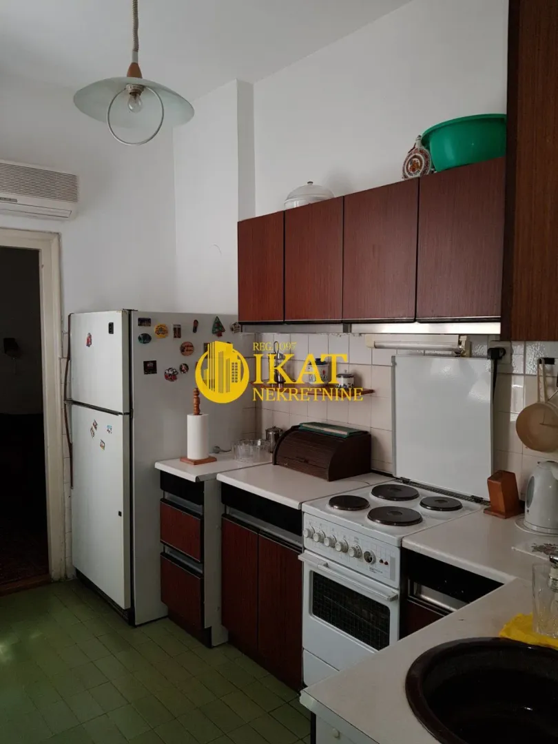 Kuhinja opremljena drvenim elementima, šporetom i frižiderom.
