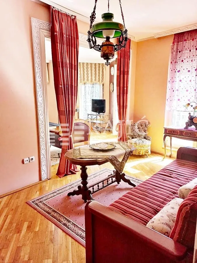 Living room with sofa, rug, and traditional furniture.