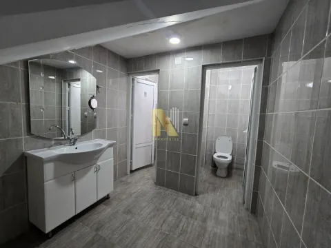 Tiled bathroom with a washbasin and a toilet in the background. - image 17