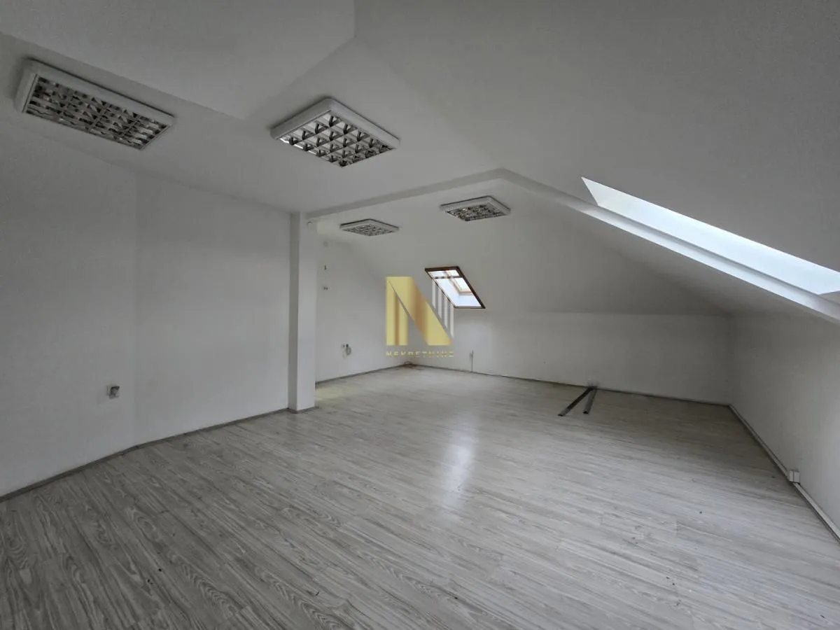 Empty attic room with laminate flooring and skylights.