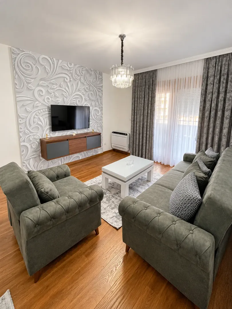Living room with a sofa set, TV, and decorative wall.