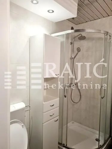 Smaller bathroom with a shower cabin and white furniture.