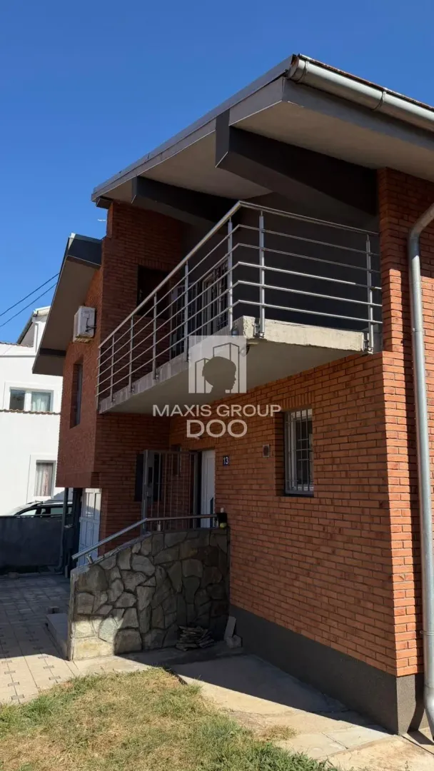 Spoljašnji izgled kuće sa fasadom od cigle i balkonom.