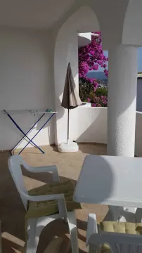 Covered terrace with outdoor seating and a view of flowers. - image 10