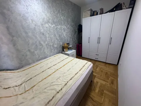 Bedroom with a bed, white wardrobe, and parquet flooring. - image 6
