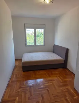 Spavaća soba sa bračnim krevetom, drvenim parketom i prozorom. - image 2