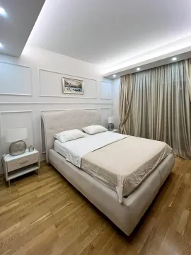 Prostrana spavaća soba sa bračnim krevetom, noćnim stočićima i dekorativnim zidnim lajsnama. - image 9