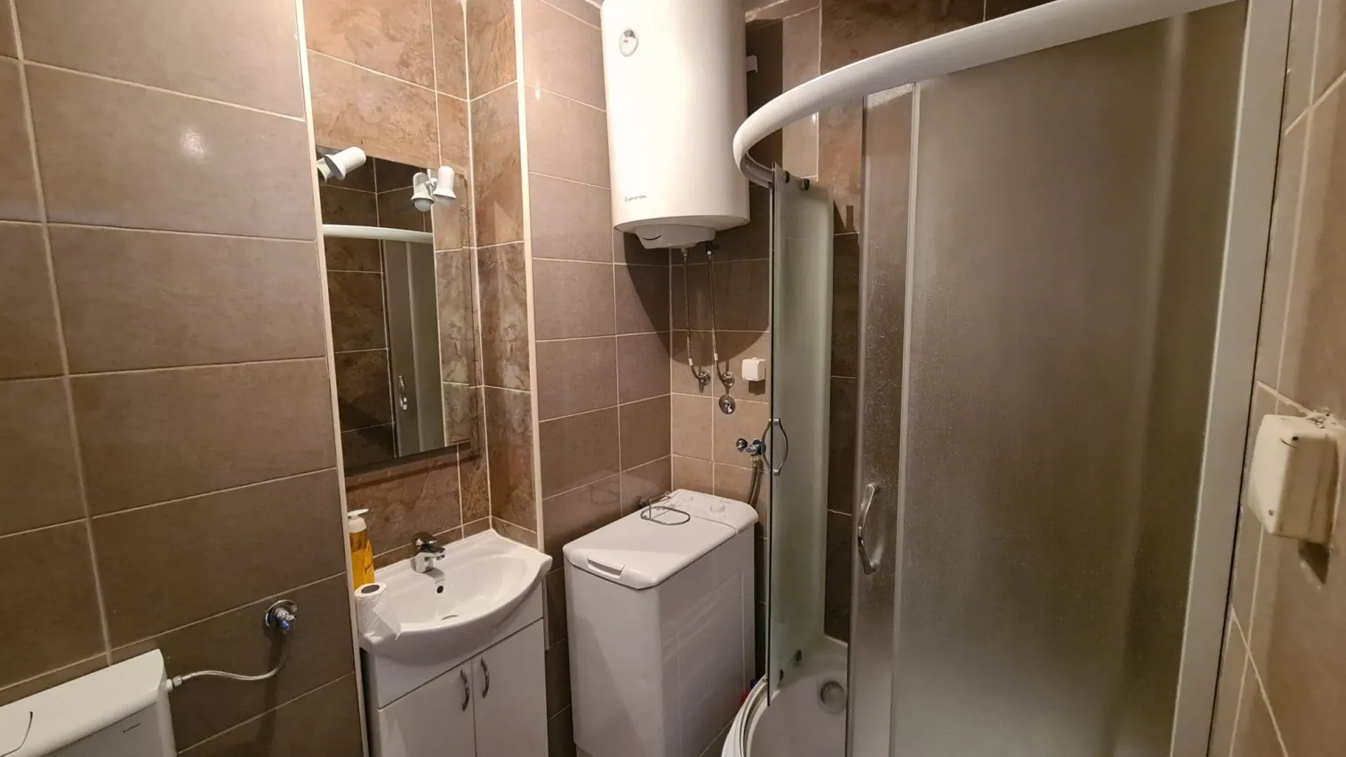 Bathroom equipped with a shower cabin, washbasin, water heater, and washing machine.