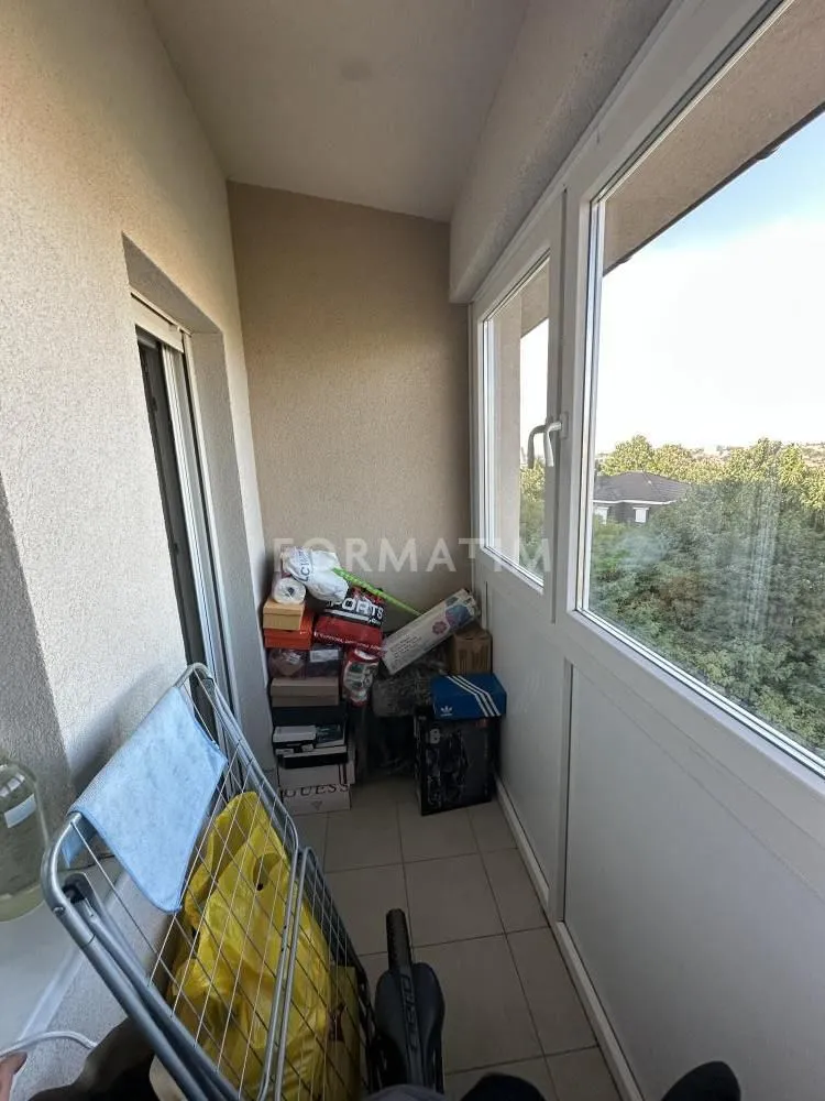 Zastakljeni balkon sa odloženim stvarima i stalkom za sušenje veša.