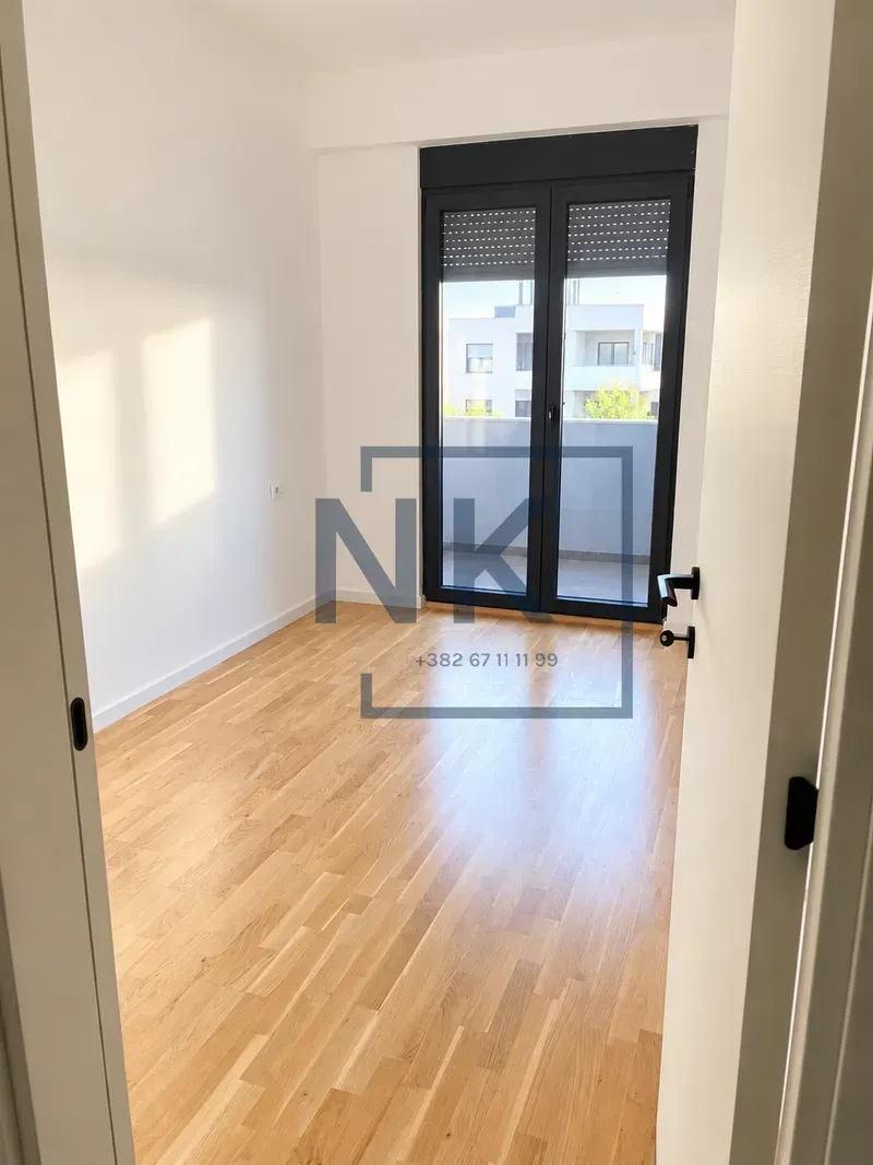 Empty room with hardwood flooring and balcony doors.