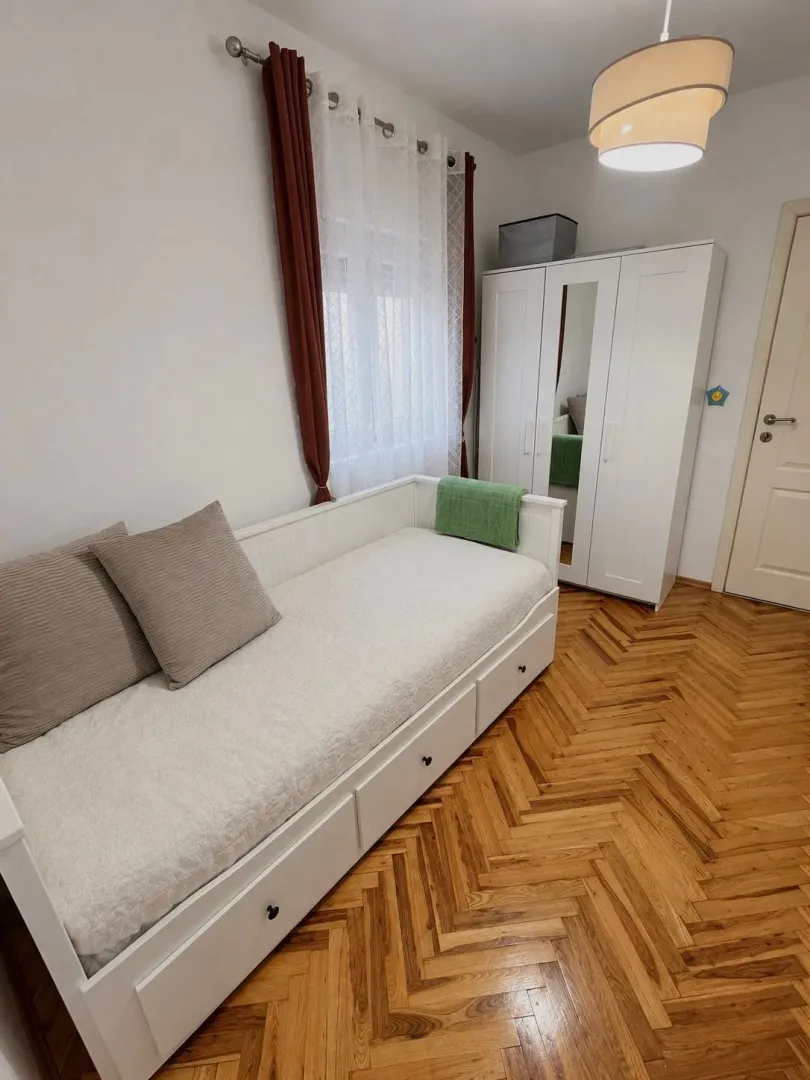 Small bedroom with a pull-out bed and a white wardrobe.