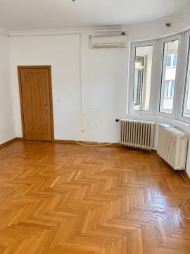 Empty room with wooden parquet flooring, a wooden door, and a window with radiators. - image 6