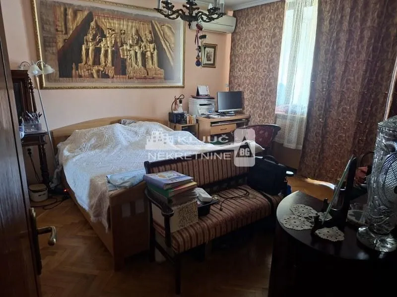 Nameštena spavaća soba sa bračnim krevetom, radnim stolom i parketom.