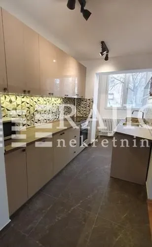 Modern kitchen with beige cabinets and built-in appliances.