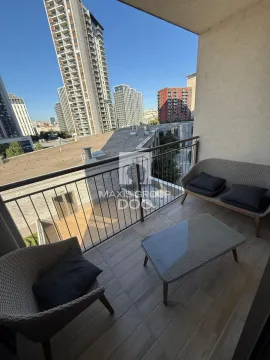 Namešten balkon sa garniturom za sedenje i pogledom na grad. - image 3