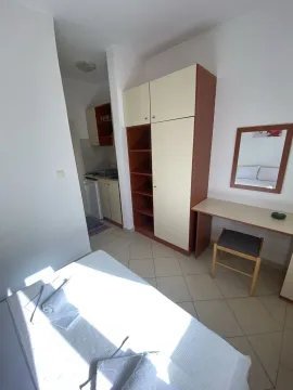 Svijetla spavaća soba sa ormarom, radnim stolom i kuhinjom u pozadini. - image 3