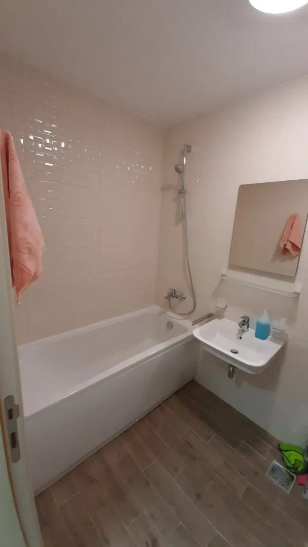 Kupatilo sa bijelim pločicama, kadom i lavaboom.