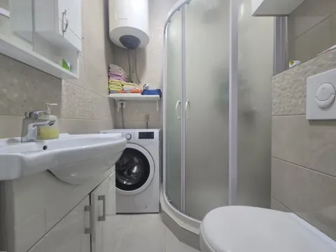 Small bathroom with a shower cabin, sink, and washing machine. - image 8