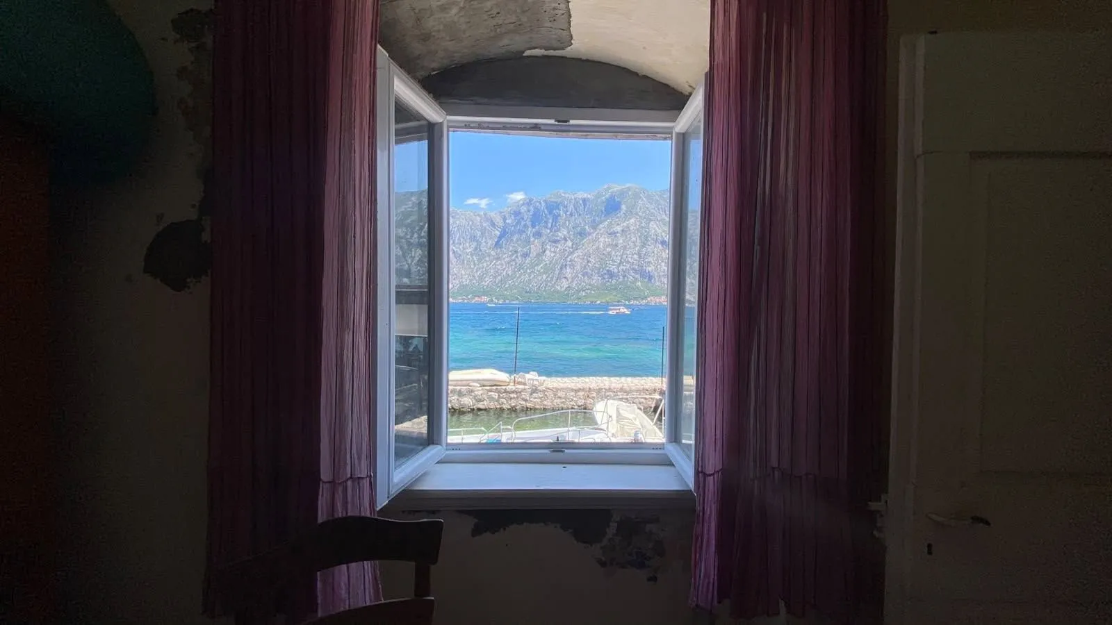 Pogled na more i planine kroz prozor sobe.