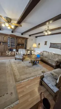 Dnevna soba sa garniturom za sedenje, drvenim gredama na plafonu i stilskim nameštajem. - image 14