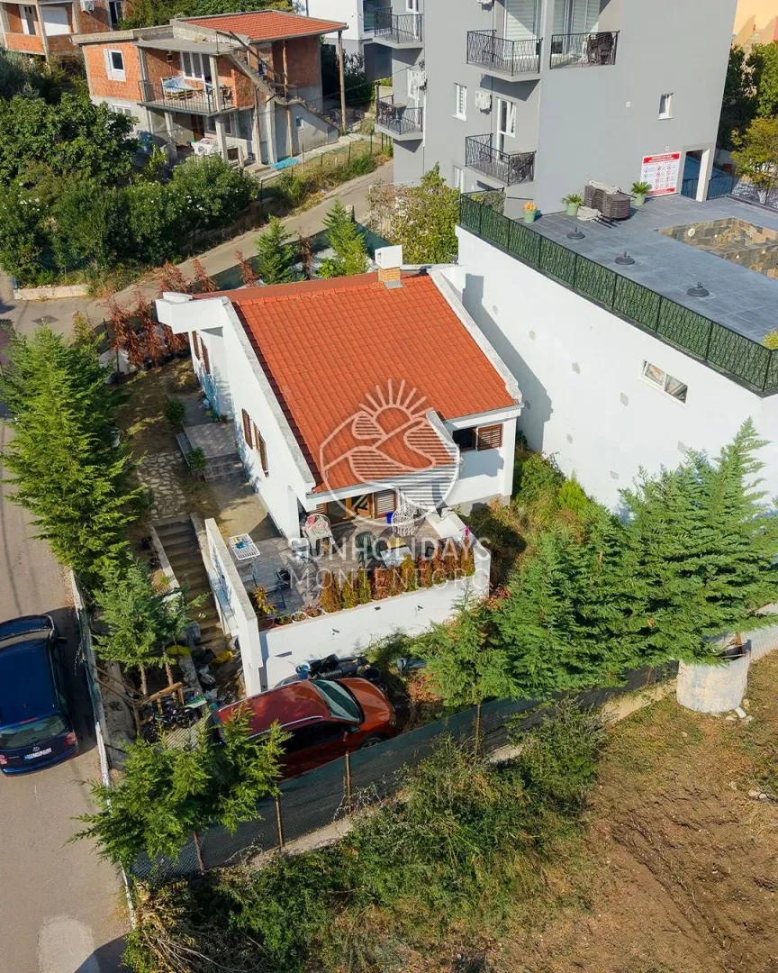 Pogled iz vazduha na kuću sa crvenim krovom i dvorištem.