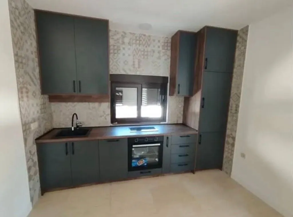 Modern kitchen with dark cabinetry and a built-in oven.