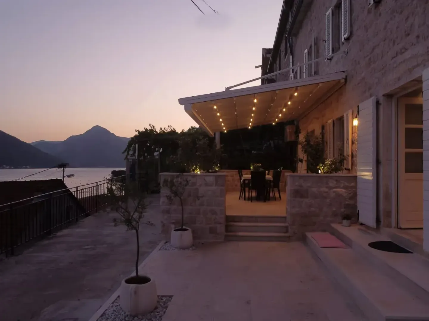 View of the exterior of the house and terrace at dusk with a sea view.