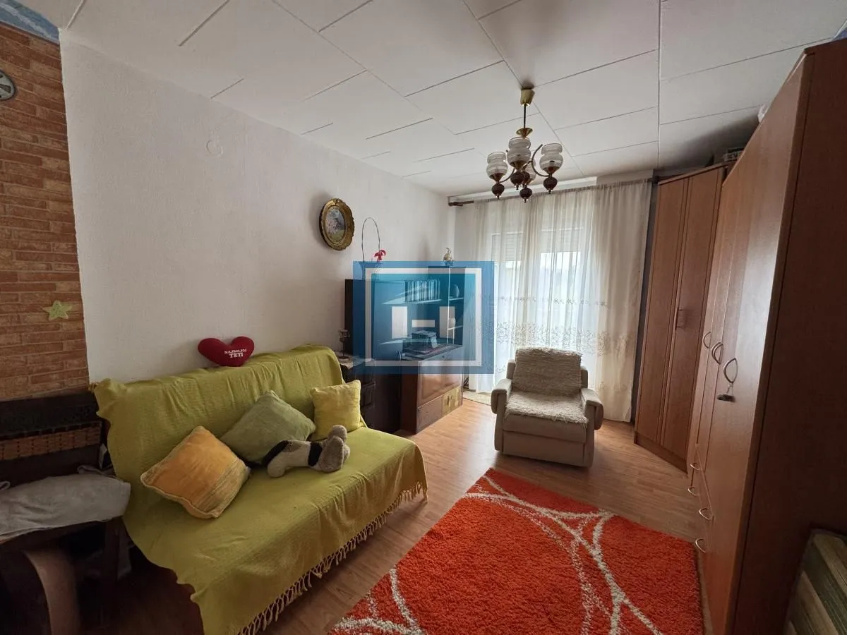 Dnevna soba sa kaučem, foteljom i drvenim ormarima.