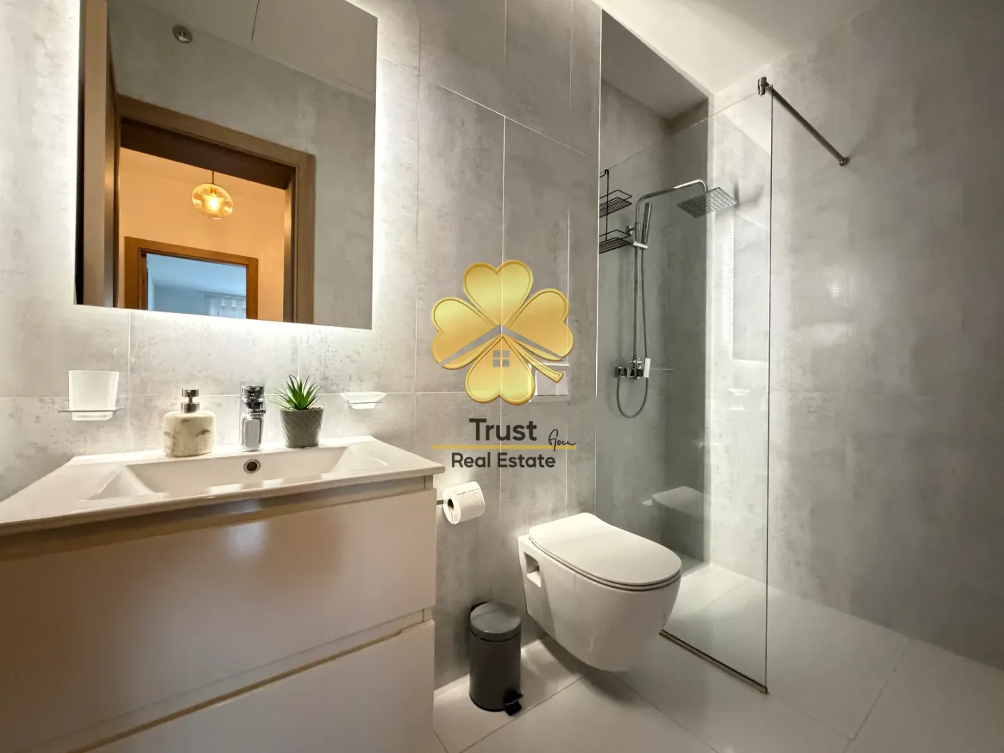 Modern bathroom with sink, walk-in shower, and toilet.