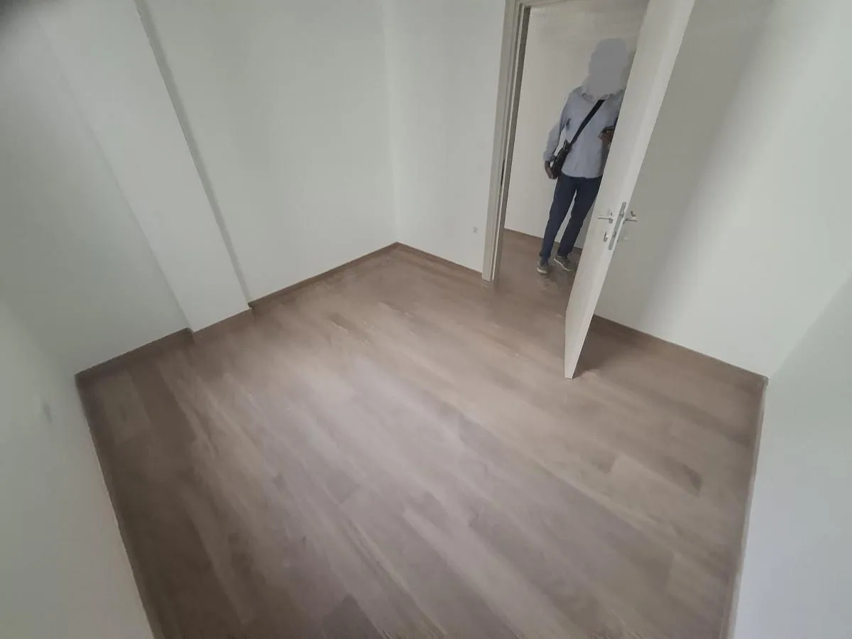 Prazna soba sa laminatnim podom i otvorenim vratima.