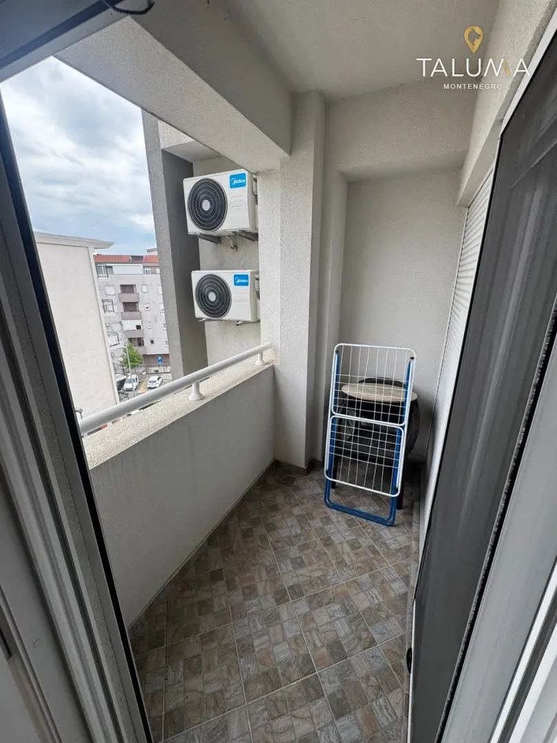 Manji natkriveni balkon sa spoljnim jedinicama klima uređaja i stalkom za sušenje veša.