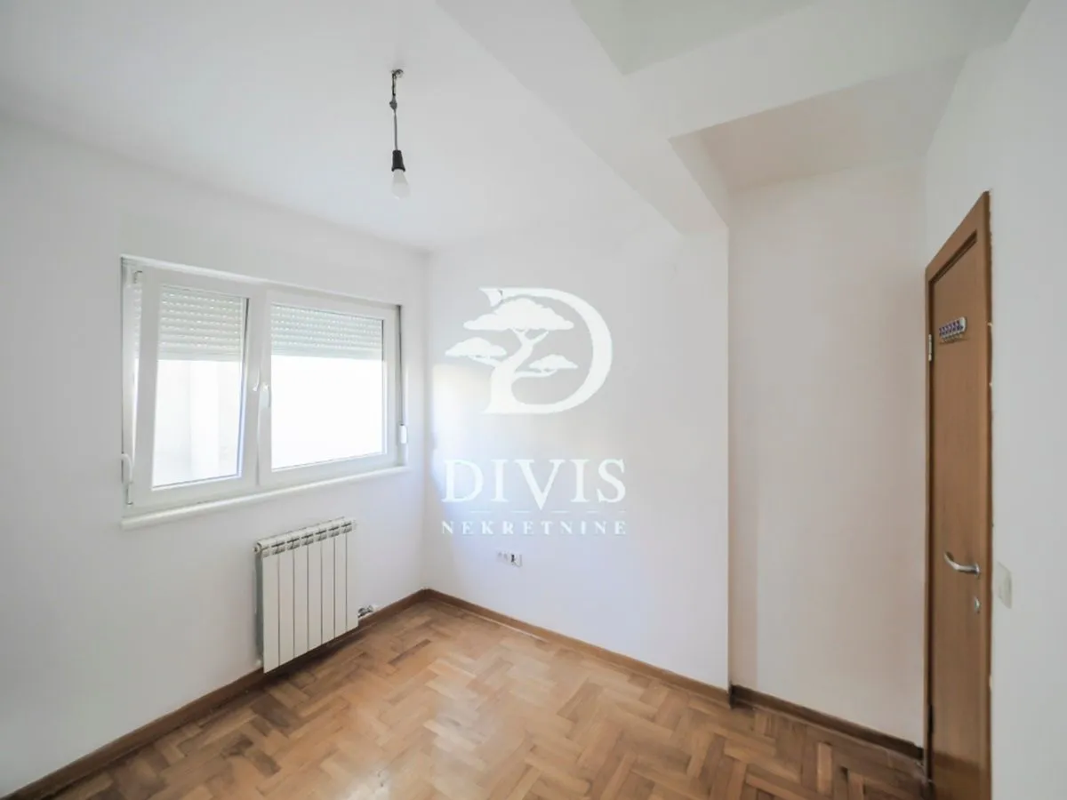Empty room with white walls, parquet flooring and a window.