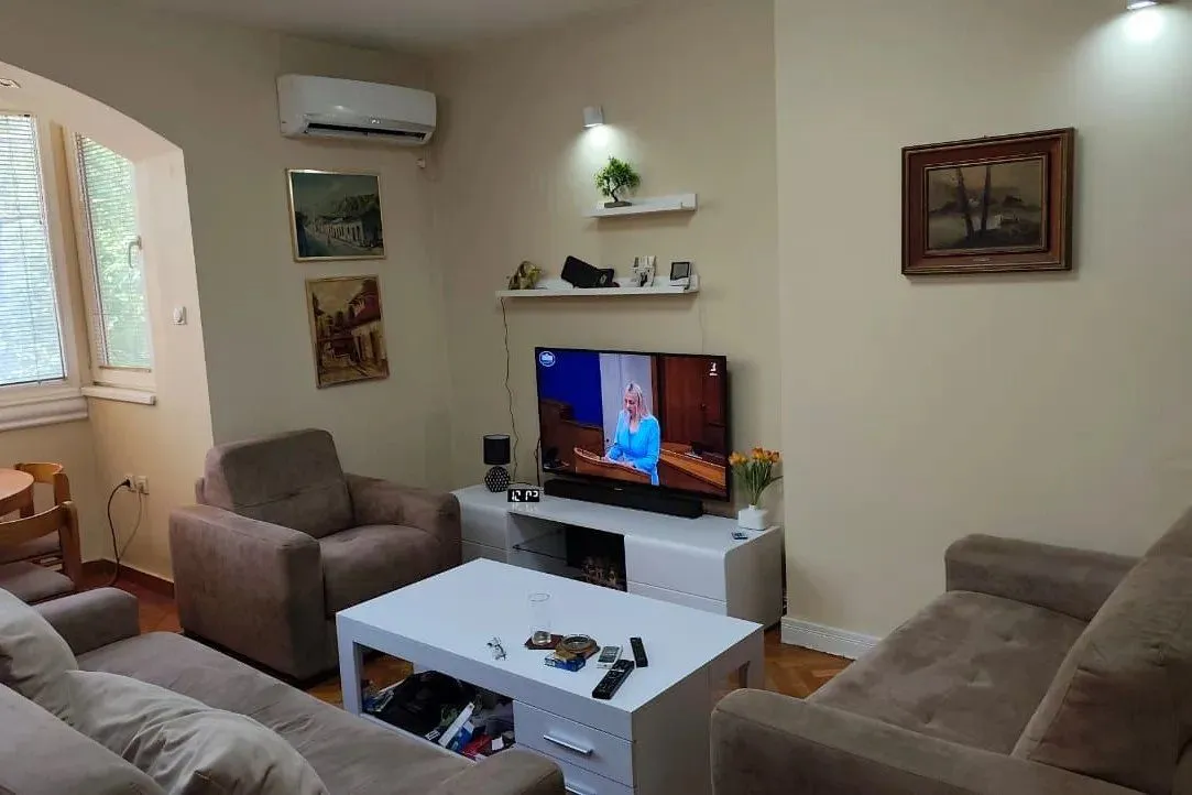 Dnevna soba sa garniturom, stočićem i televizorom.