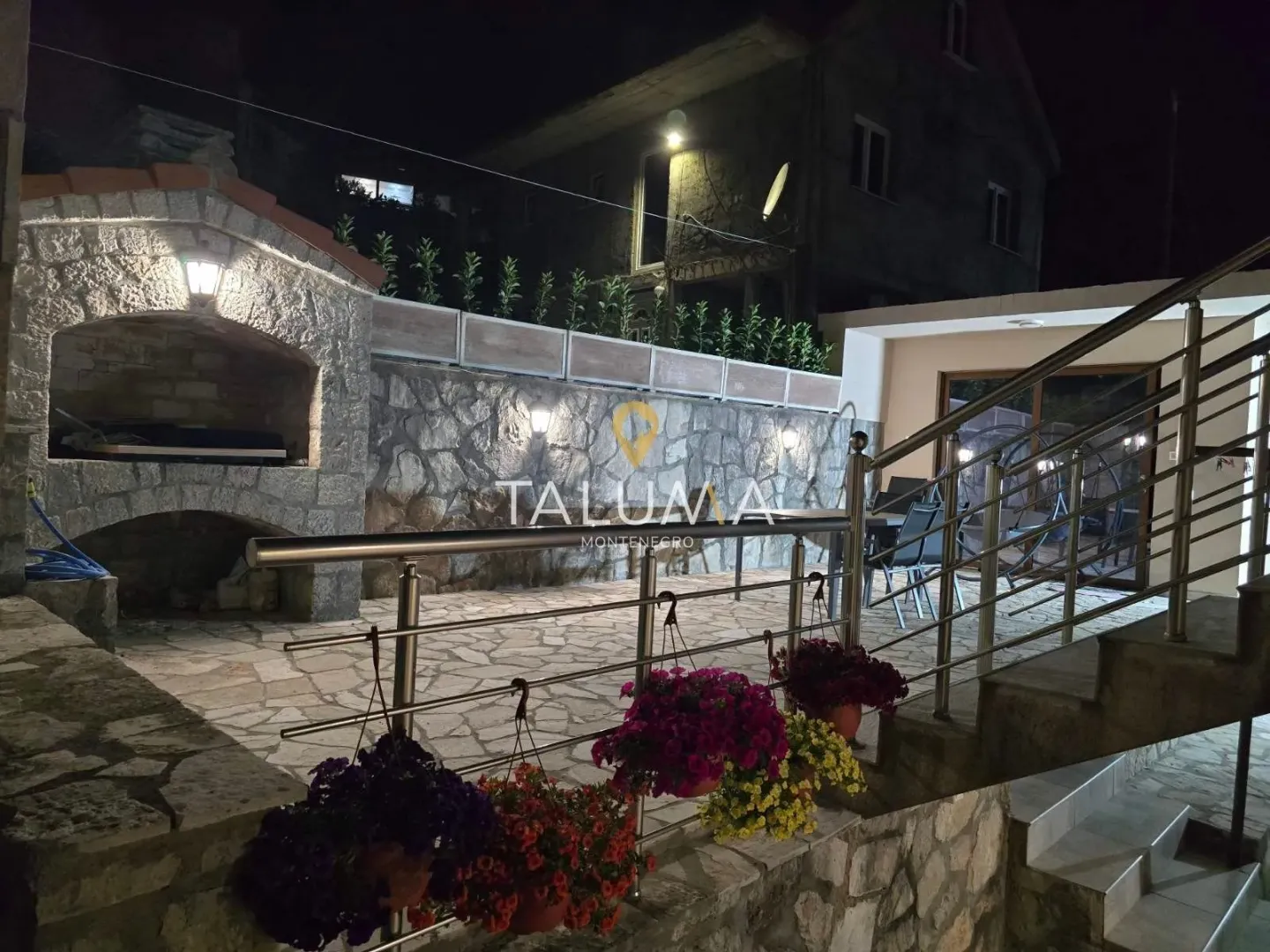 Night view of the courtyard with a stone barbecue, terrace, and stairs.