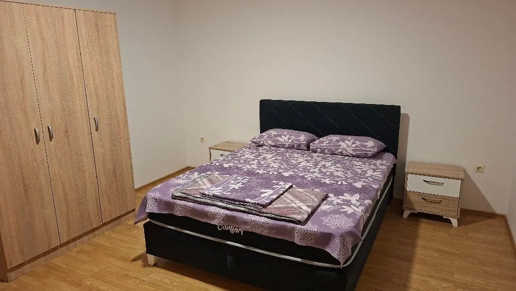 Spavaća soba sa bračnim krevetom, garderoberom i noćnim stočićem.