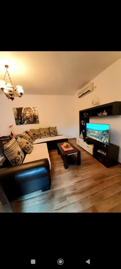 Living room with a sofa set, TV unit, and dining table.