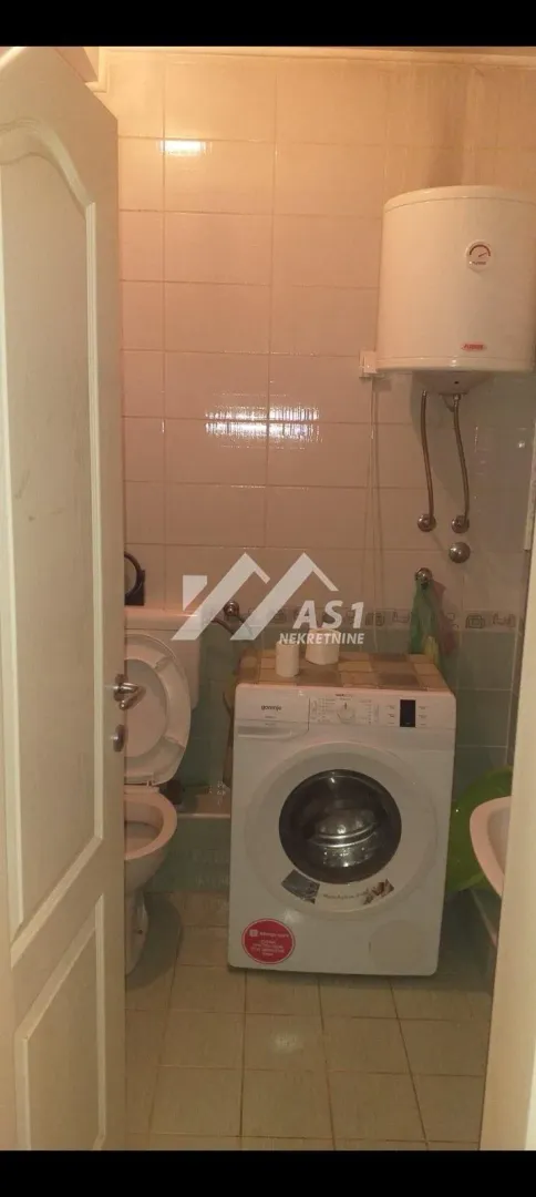 Manje kupatilo sa veš mašinom, wc šoljom i bojlerom.