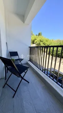 Natkrivena terasa sa crnim stolicama i pogledom na zelenilo. - image 13