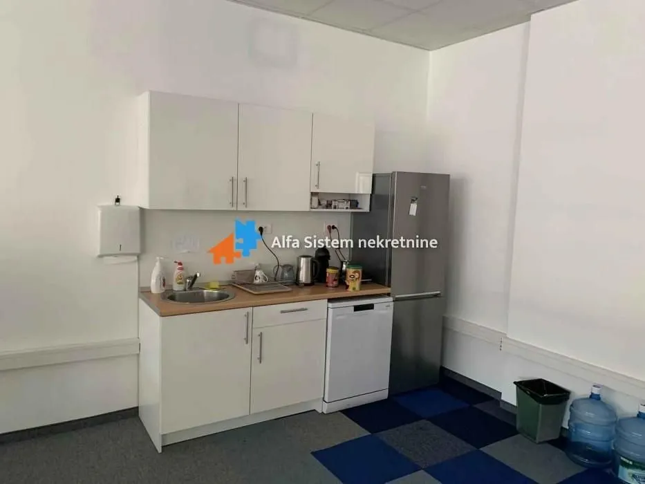 Small kitchenette with white cabinets, a refrigerator, and a sink.