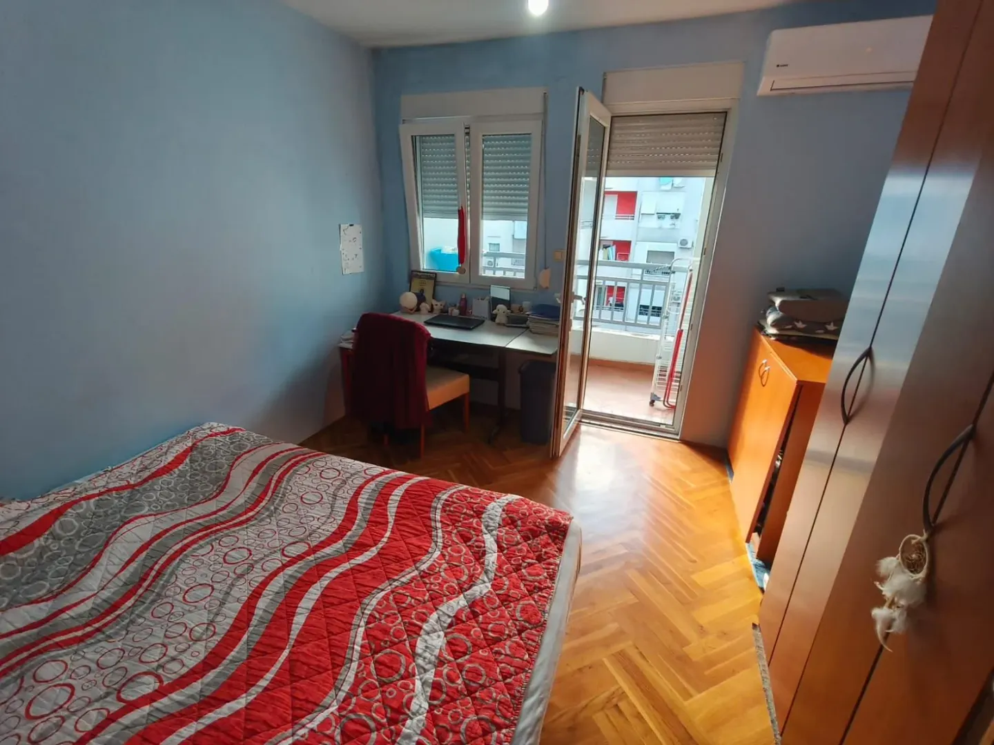 Namještena spavaća soba sa krevetom, radnim stolom i izlazom na terasu.