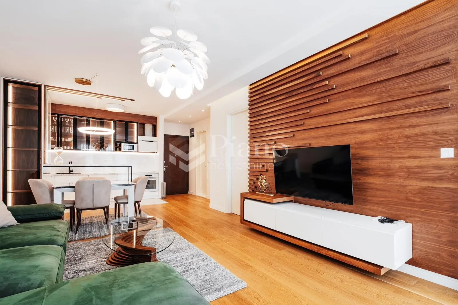 Modern living room with a wooden wall panel and a dining area in the background.