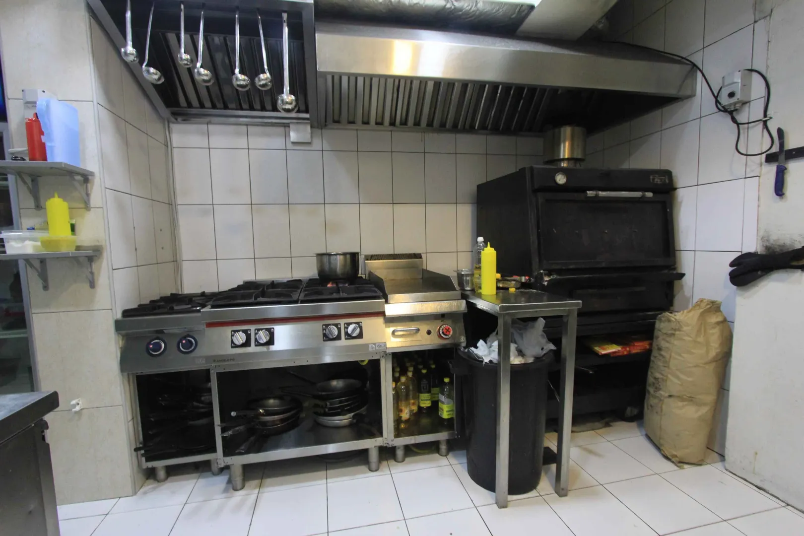 Commercial kitchen with a stove, oven, and kitchen utensils.