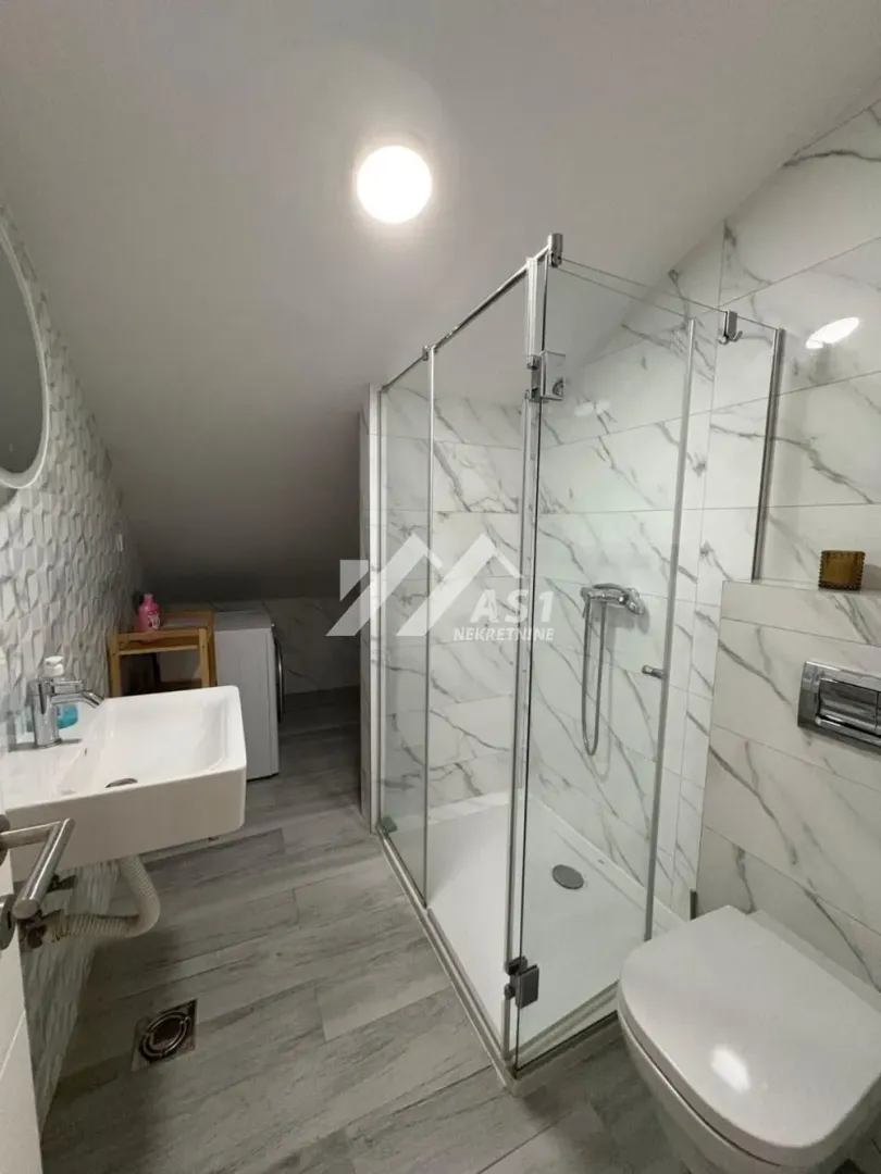 Moderno kupatilo sa tuš kabinom, umivaonikom i wc šoljom.