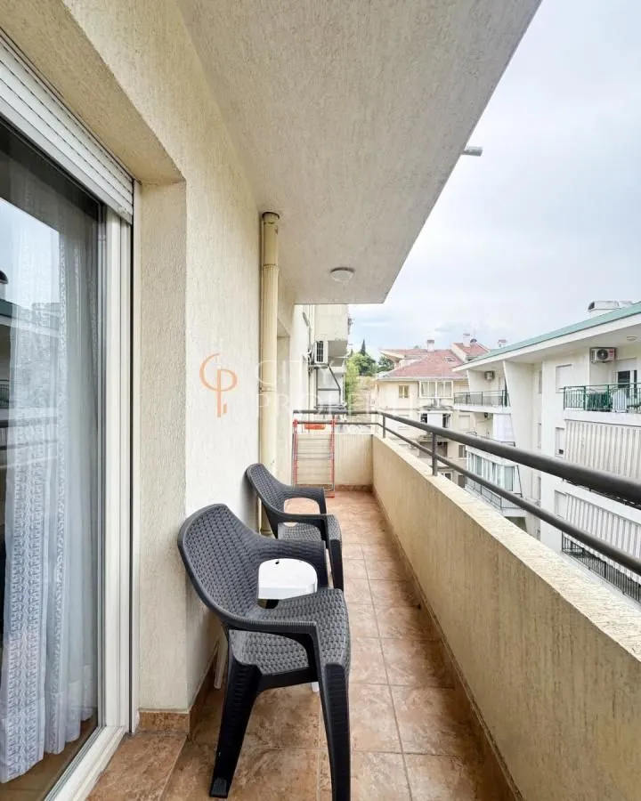Covered balcony space with chairs and a view of surrounding buildings.